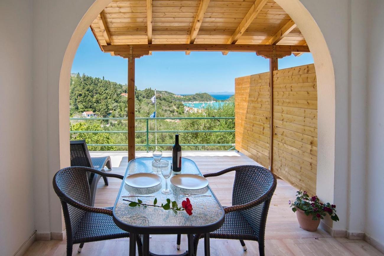 Arched balcony with a table set for two overlooking the sea and wooded coastline