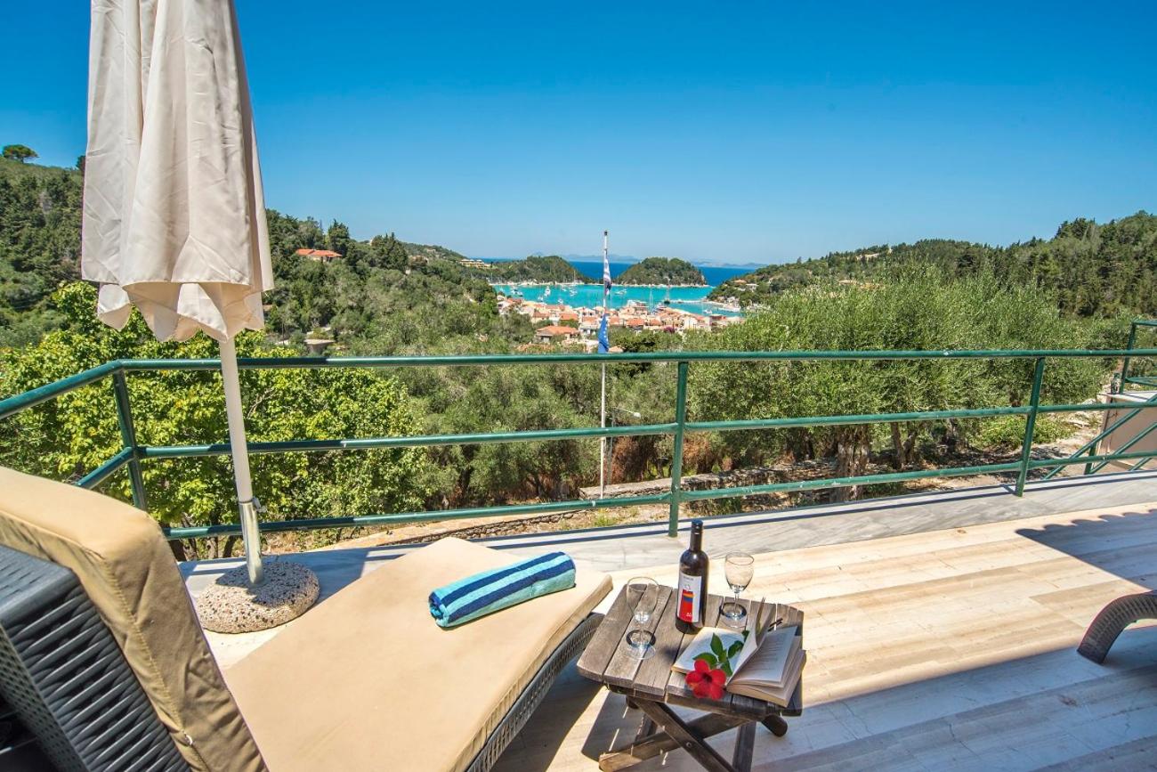 Sun terrace with lounger, umbrella and wine overlooking the coastal bay at sunset