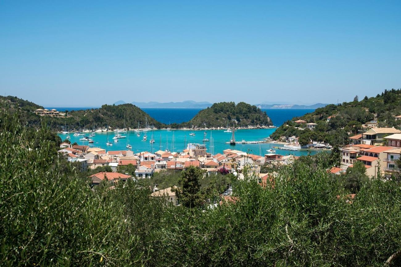 Crescent bay of Lakka with anchored sailboats and olive-covered hills